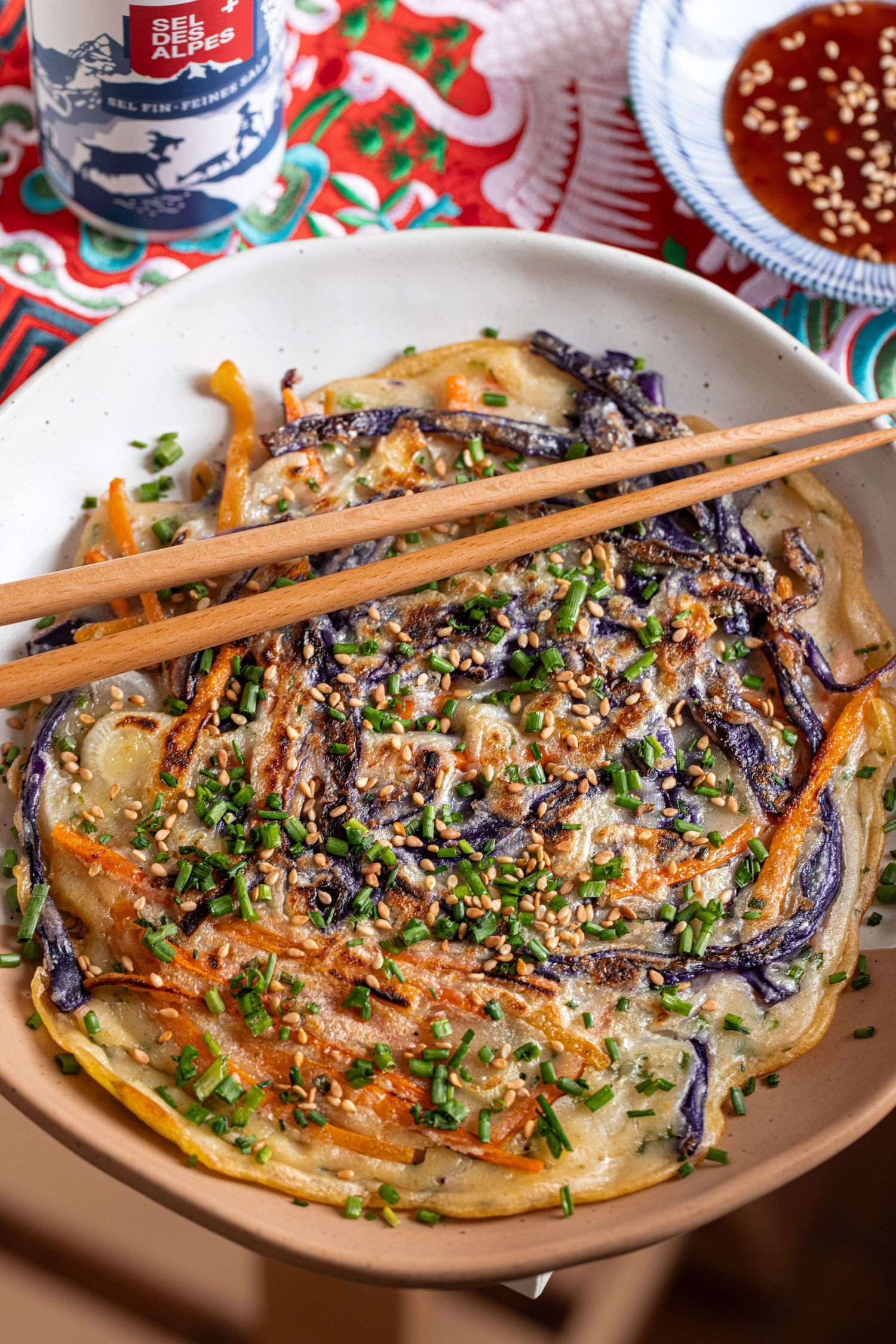 Okonomiyaki Japanese savory pancake topped with bonito flakes, green onions and sauce served with chopsticks.