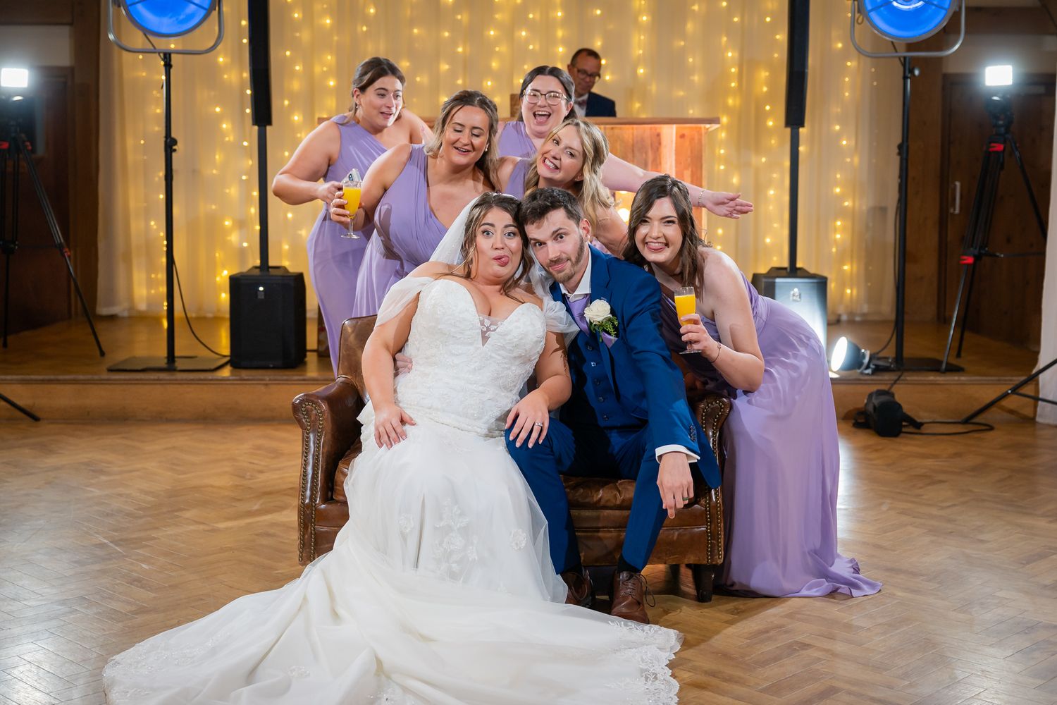 Fun photos during the Sofa crash with the bride, groom, and several guests all laughing in the main barn at an Old Kent Barn wedding.
