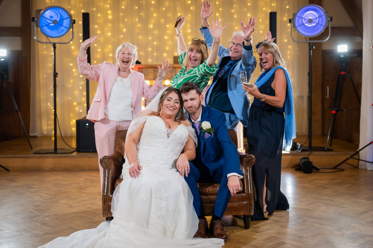 An Old Kent Barn wedding sofa crash with the bride, groom, and several guests all laughing and being joyful.