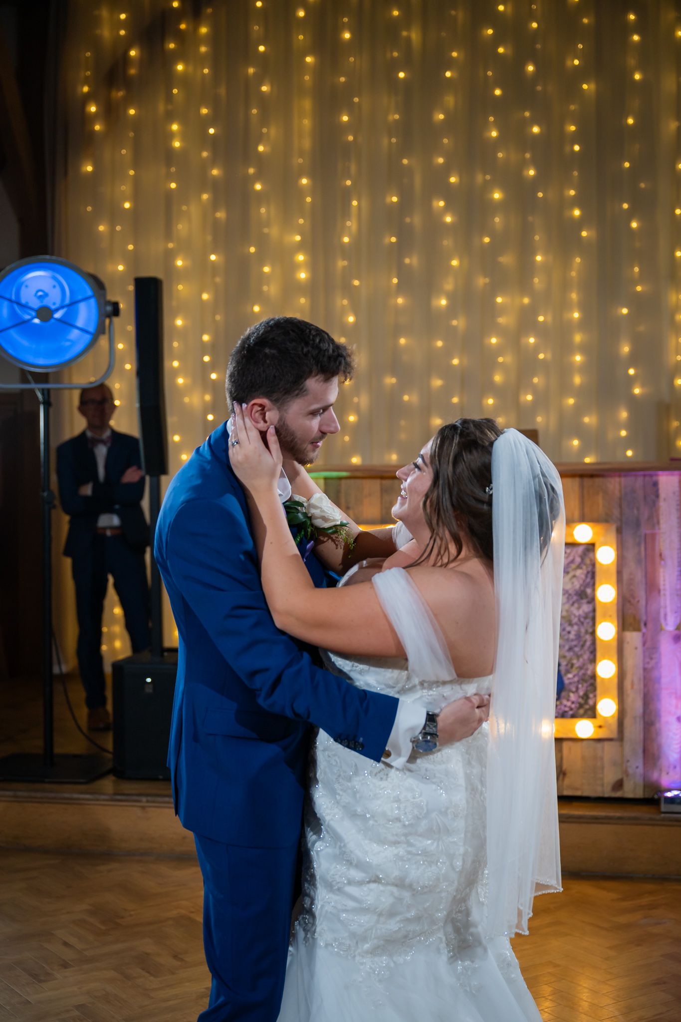 Bride and groom share their first dance, embracing under warm fairy lights at their wedding reception.