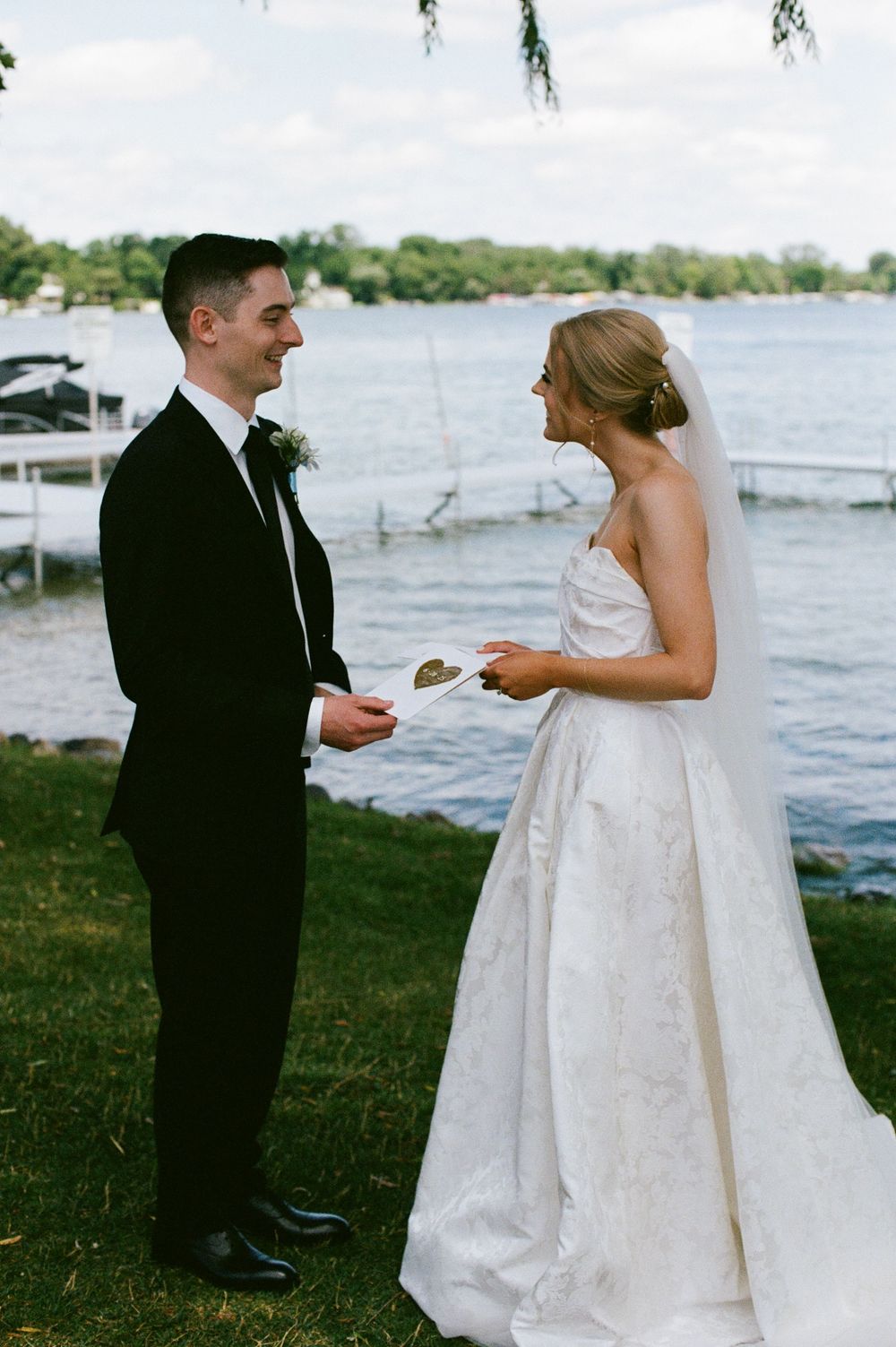 Bride and groom exchange private vows by lakeside during intimate outdoor first look moment.