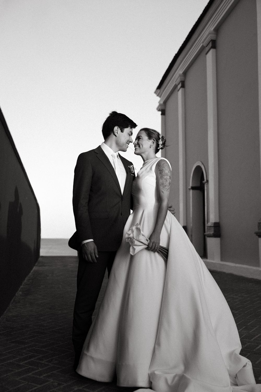 Bride and groom share romantic moment gazing at each other outside historic building after wedding.
