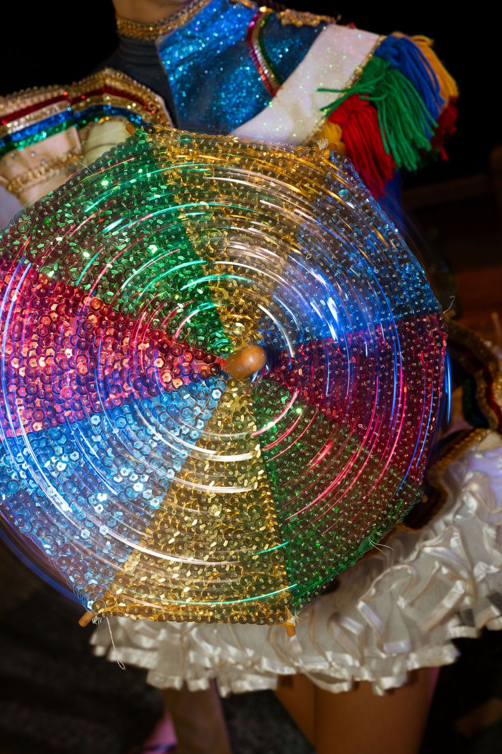 Colorful spinning sequined umbrella with rainbow glitter design at a festive carnival celebration.