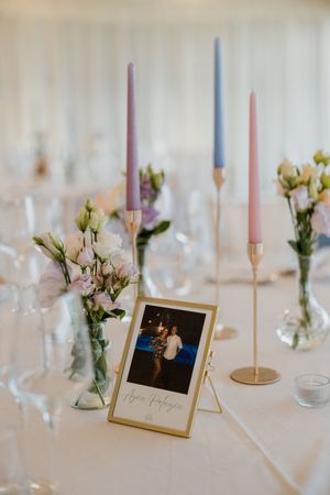 Elegant wedding table with pastel candles, white flowers, and a Polaroid photo centerpiece.