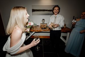 Laughing guests enjoy drinks and conversation at an intimate wedding reception gathering.