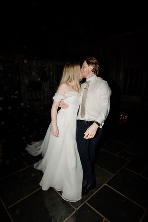 Bride and groom share a kiss on a dark dance floor during their wedding reception.