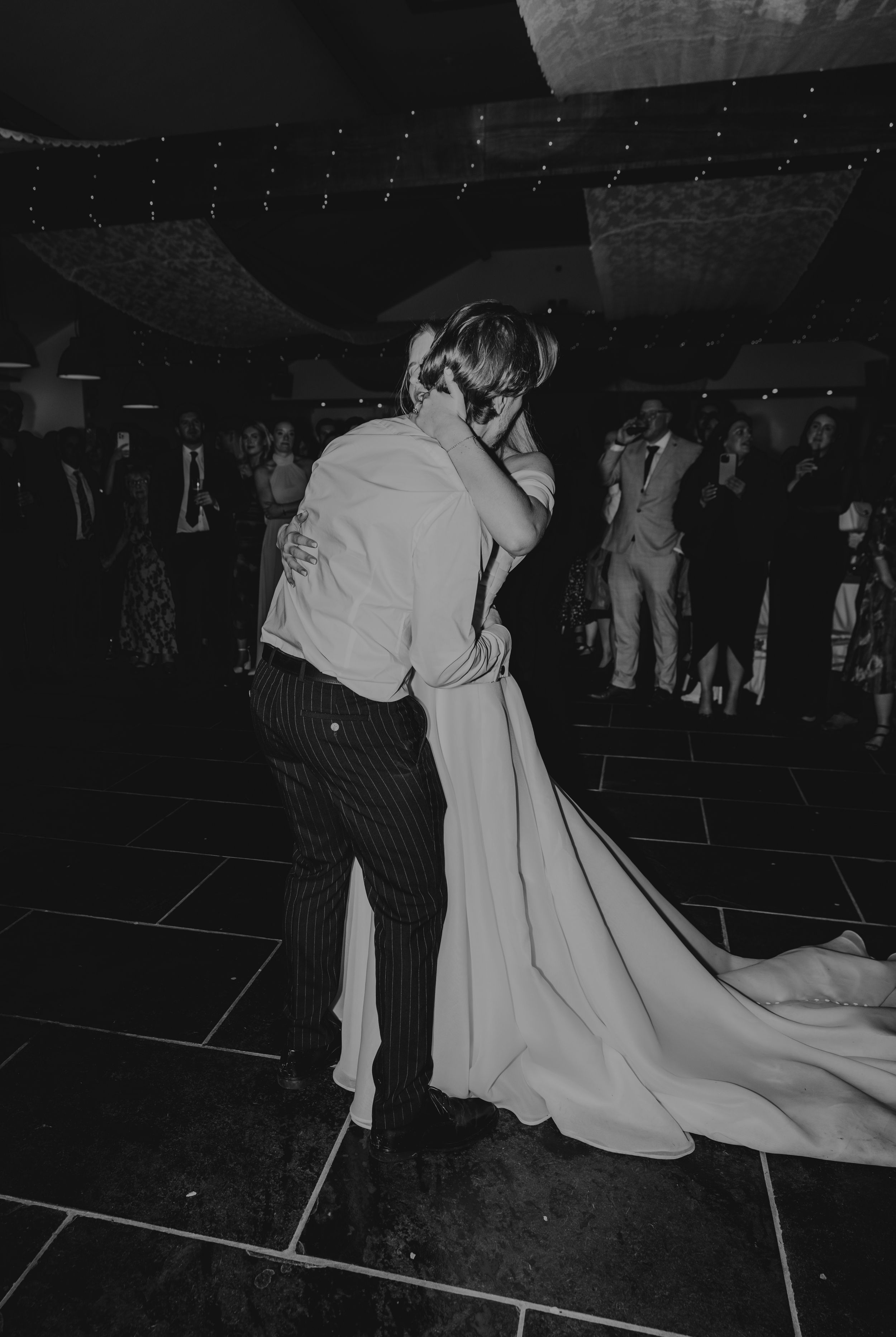 Bride and groom share intimate first dance in black and white photo.