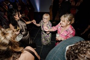 Young children dancing joyfully with guests on wedding reception dance floor.