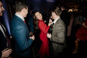 Guests dancing and socializing at wedding reception with woman in red dress on dance floor.