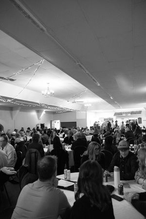 Black and white photo of a large crowded banquet hall filled with guests seated at tables during a formal event.