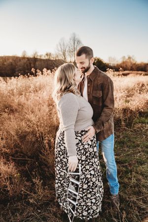 Couple sharing a tender moment in a golden autumn field at sunset.