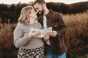 Smiling couple reading a book together in a scenic fall meadow.