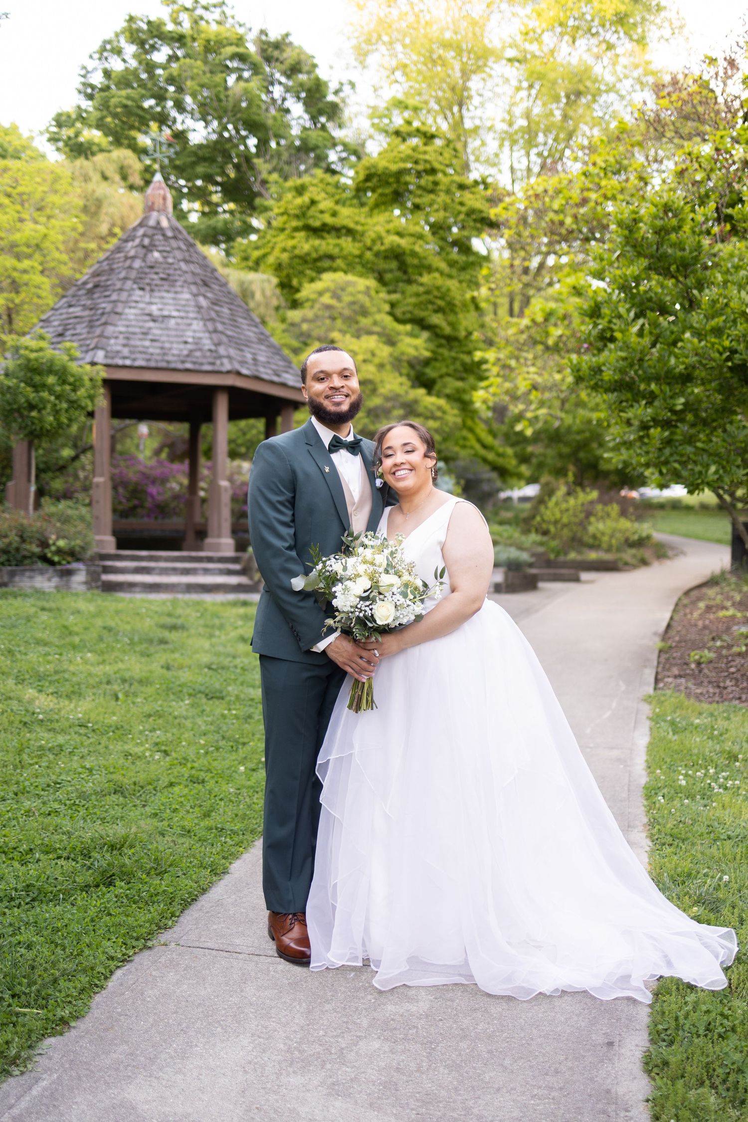 Bride and groom pose on garden path near gazebo in Eden Park Cincinnati