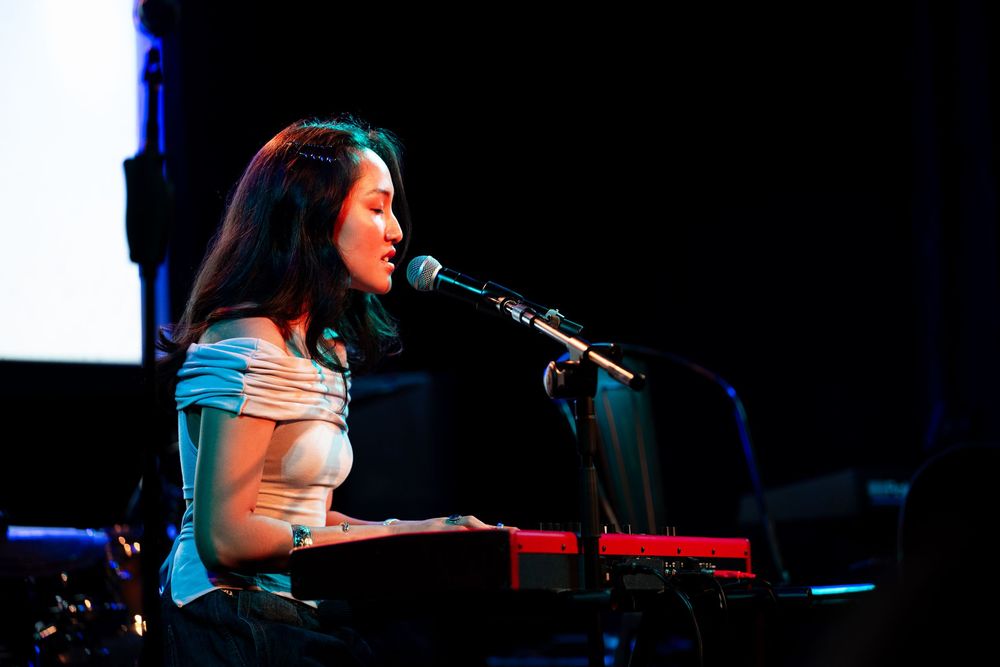 Nicole Han plays the keyboard and sings into a microphone at the paramount la.