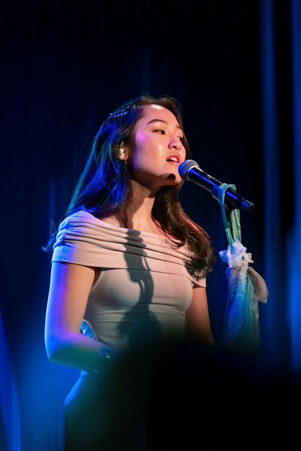 Nicole Han sings into a microphone on stage at the paramount la