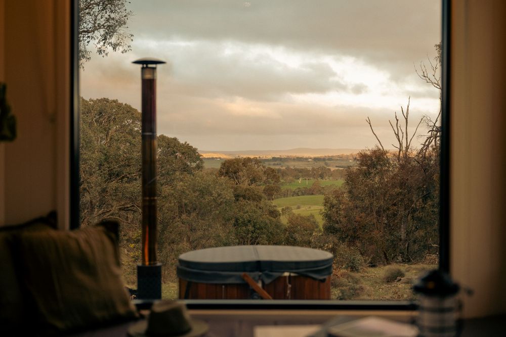 Luxury tiny home accommodation photography featuring outdoor bath and panoramic countryside views in regional Victoria