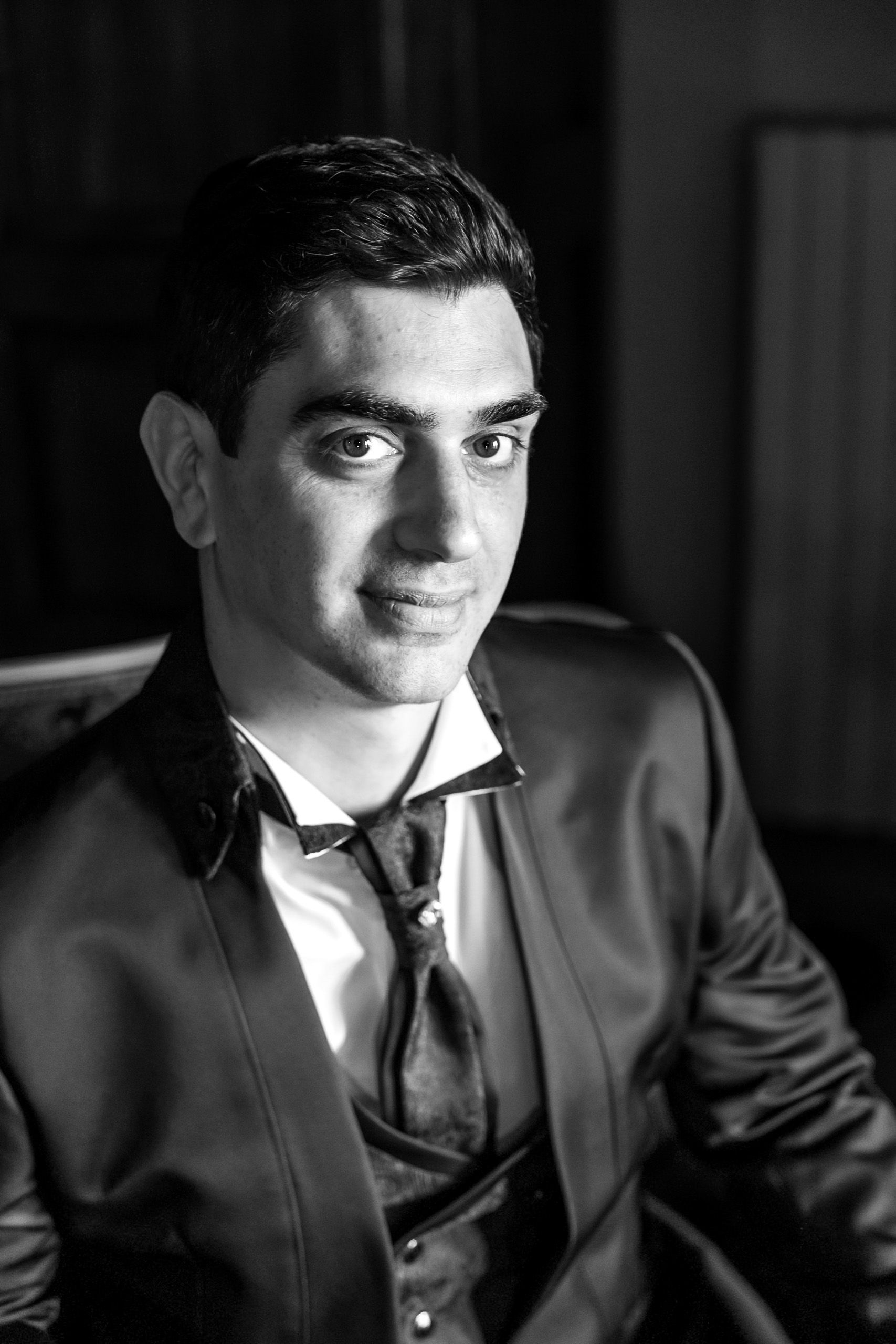 Black and white portrait of a young man in a suit and tie, looking confidently at the camera.