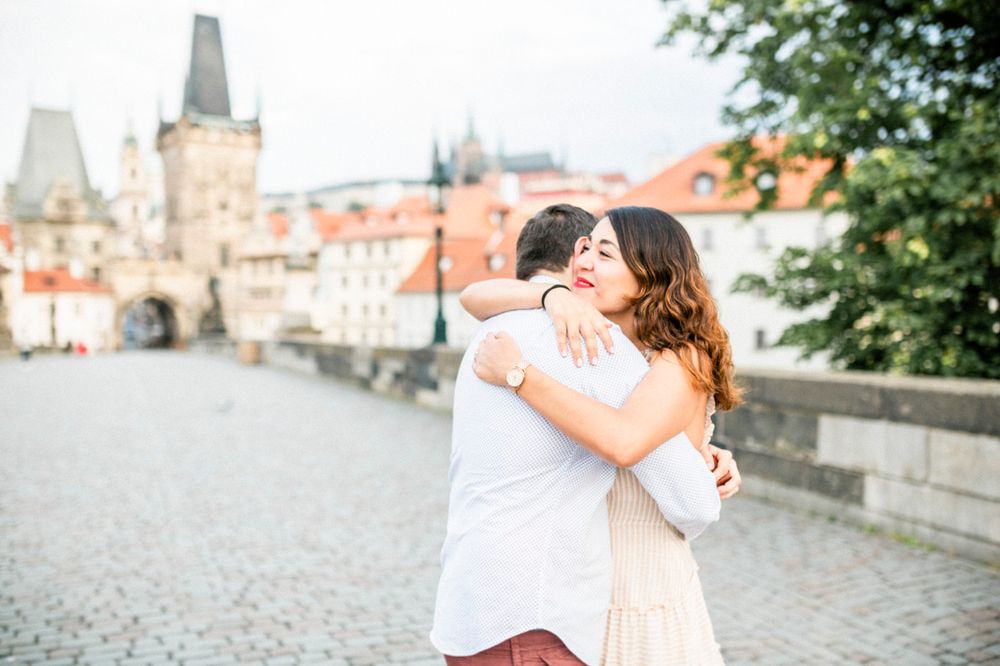 A romantic moment captured on Charles Bridge in Prague with historic towers in the background.