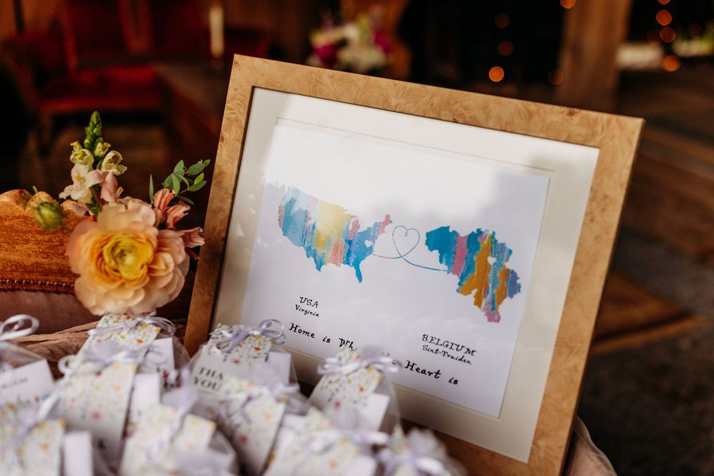 Framed watercolor map with colorful regions displayed at a wedding reception table with floral arrangements and escort cards.