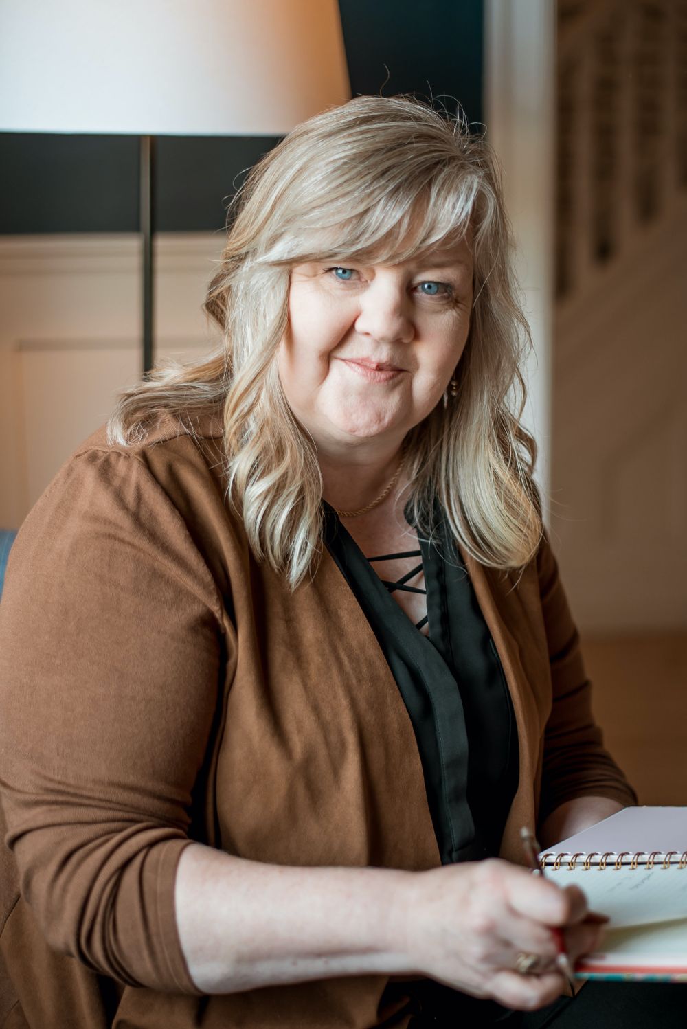 Person in brown cardigan with notebook sitting on couch during creative session.