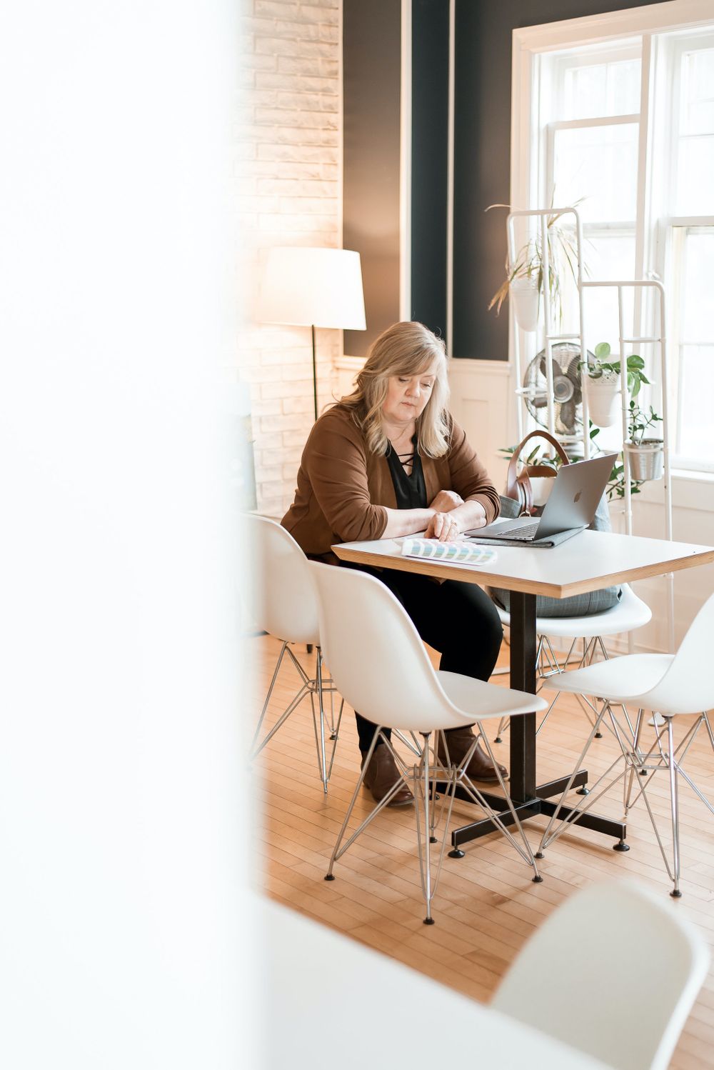 Side view of workspace setup with modern furniture and natural lighting from windows.