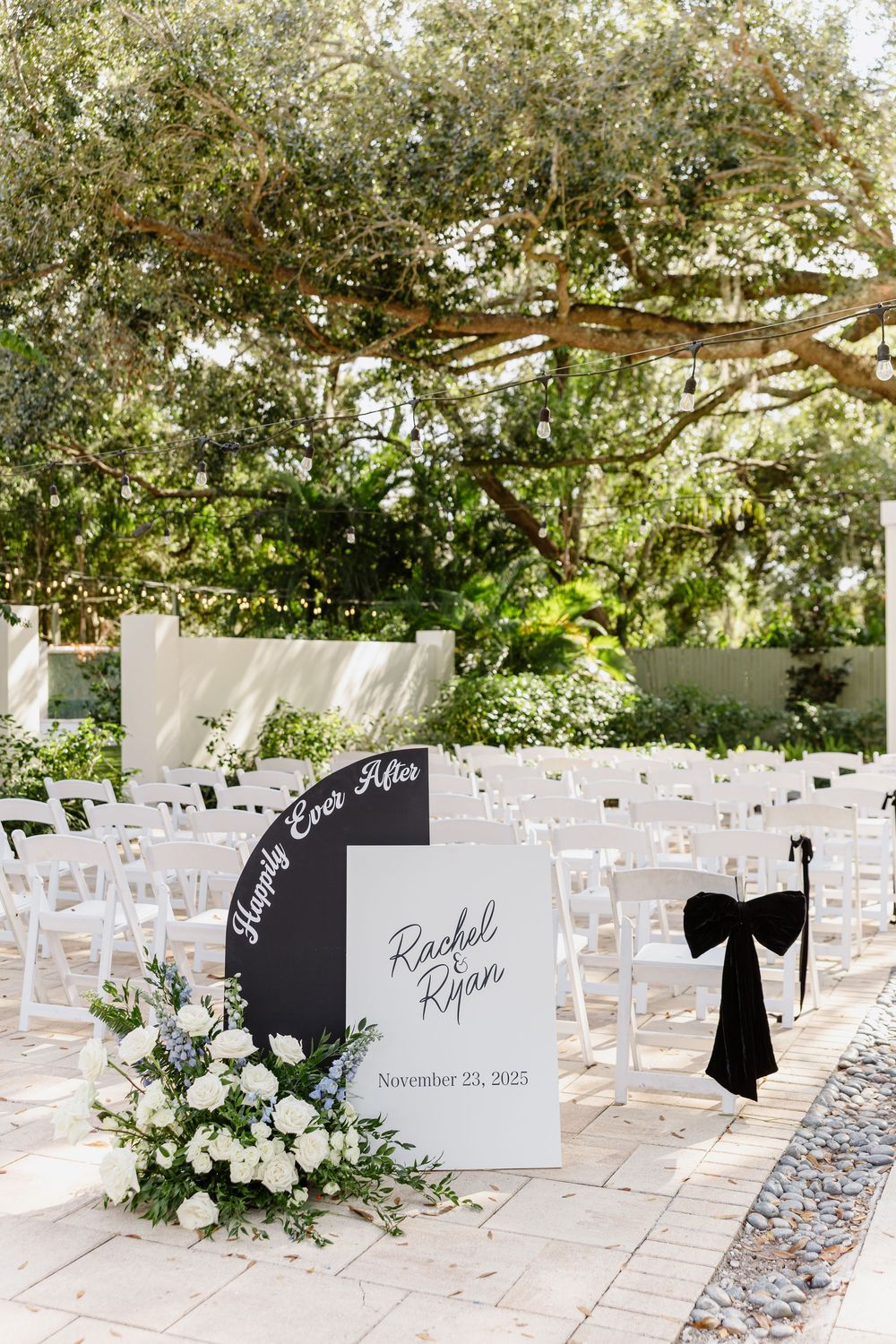 Outdoor wedding ceremony setup with white chairs, black bow accents, and a welcome sign reading Rachel & Ryan, November 23, 2025.