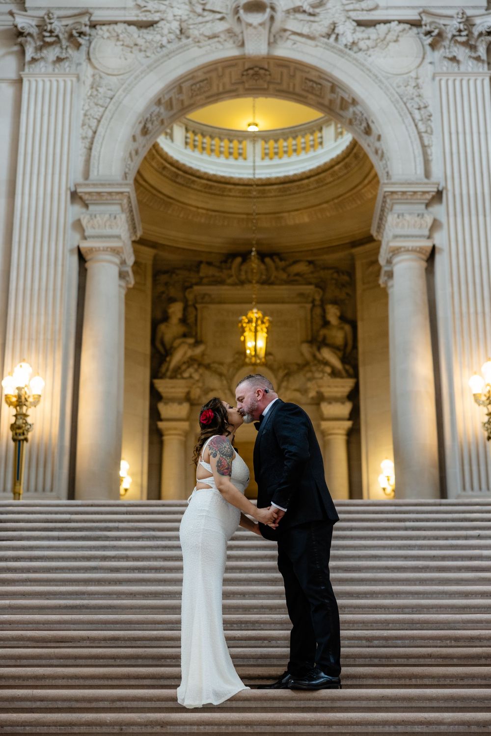 Bride and groom share a kiss on the grand staircase of San Francisco City Hall.