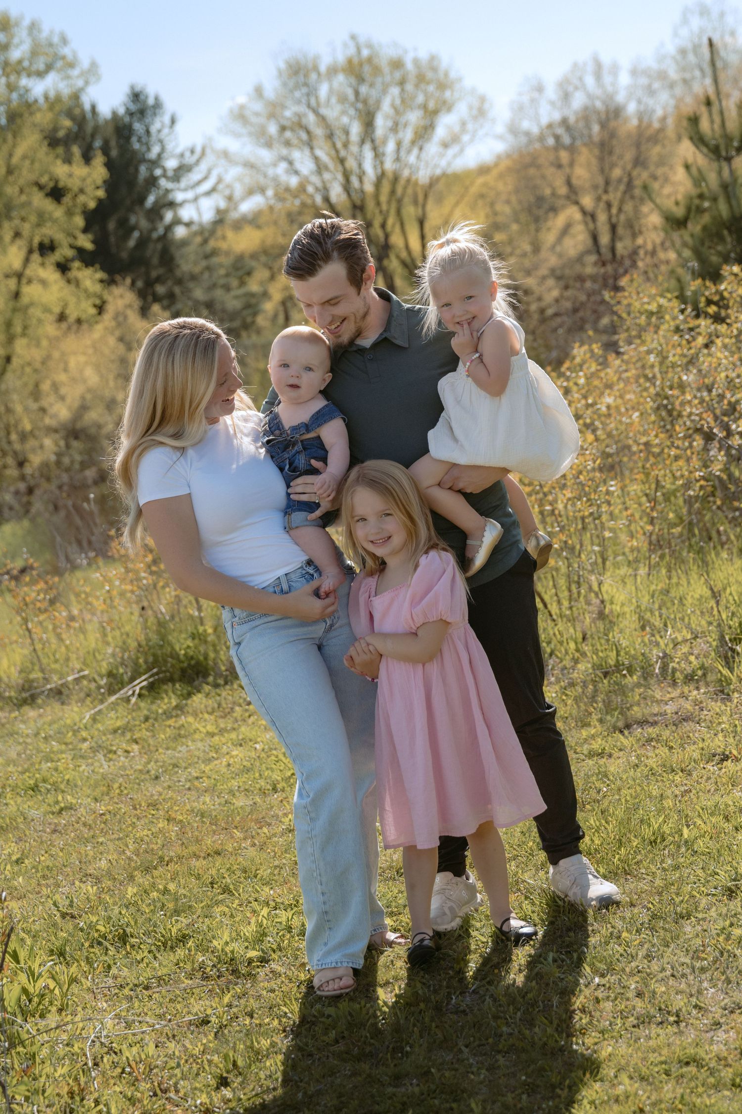 family with three toddlers smiling for a candid lifestyle outdoor spring session in hudson, WI