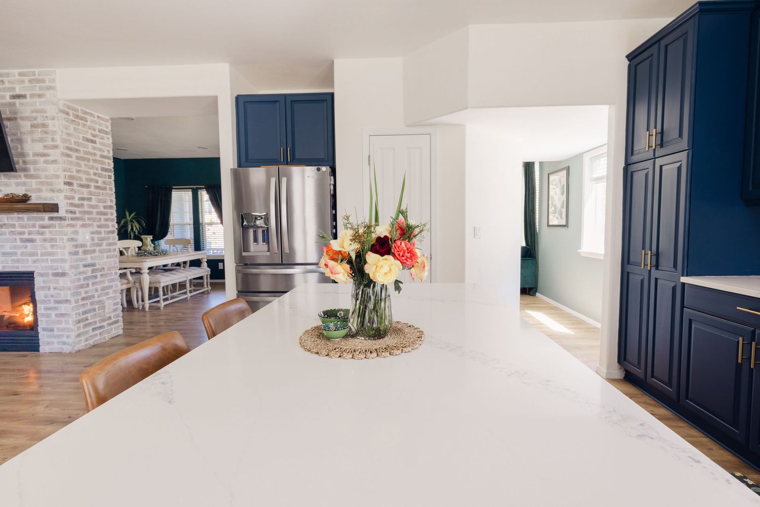 Modern white kitchen island with quartz countertop, gray cabinets, and stainless steel appliances in background.