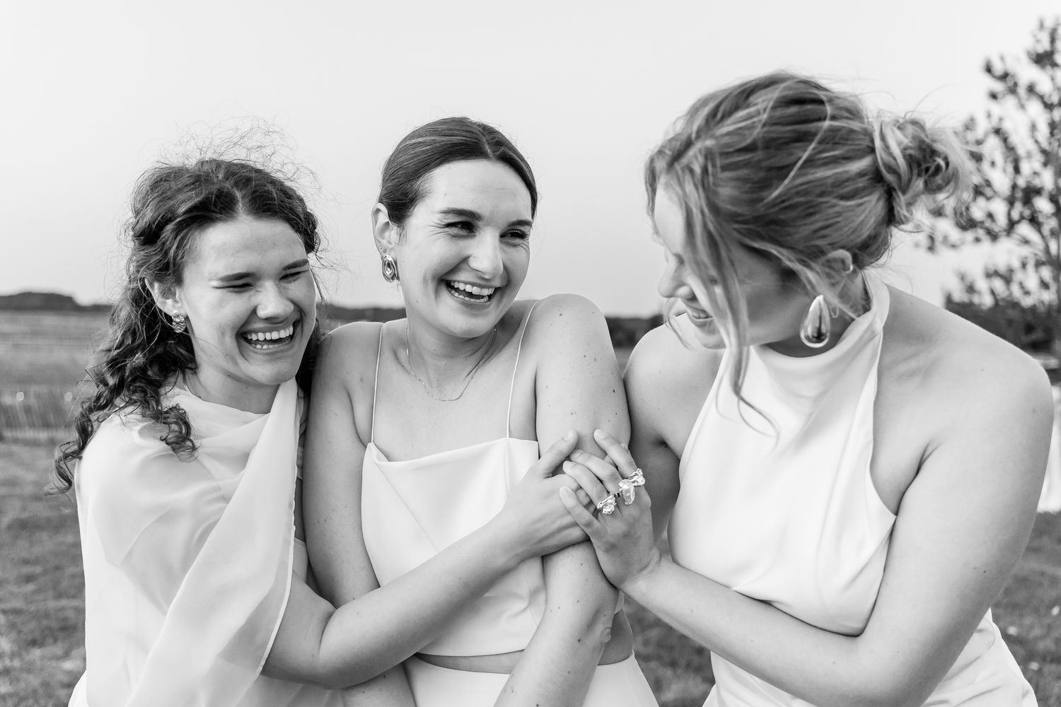 Men in white dress shirts laughing and socializing at a formal event, holding drinks in a black and white photo.