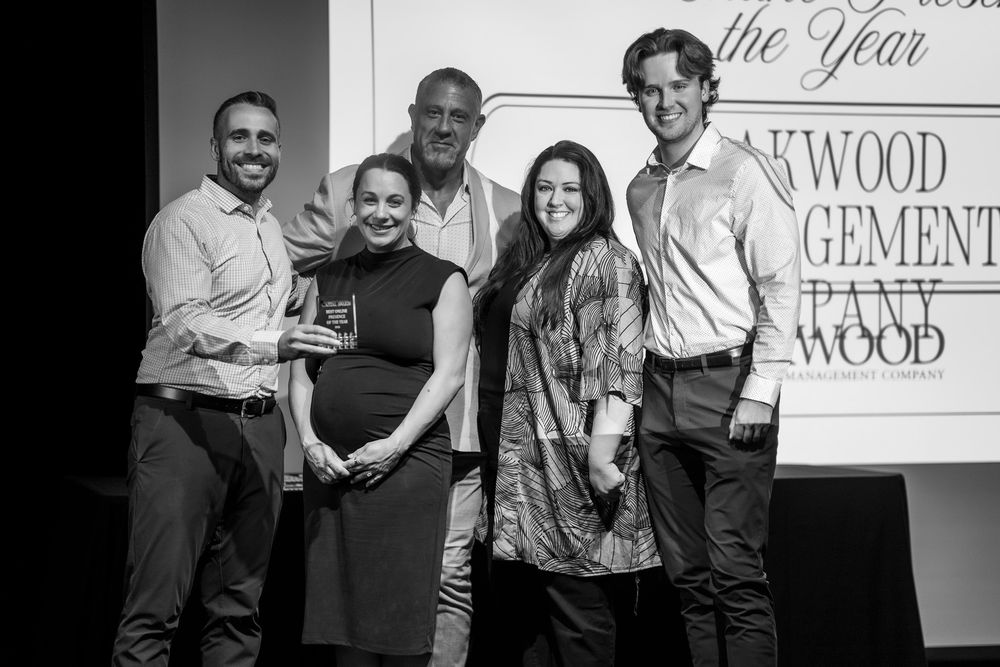 Group of five professionals posing on stage at an awards ceremony in black and white photo.