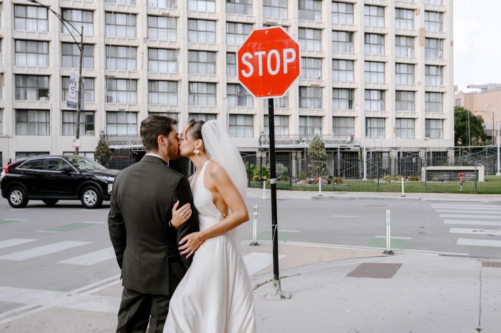 Wedding couple posing near a stop sign and modern building facade.