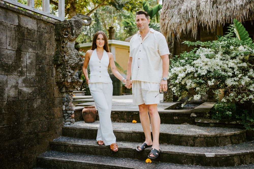 Romantic photoshoot at a stone temple with thatched roof and tropical landscaping.
