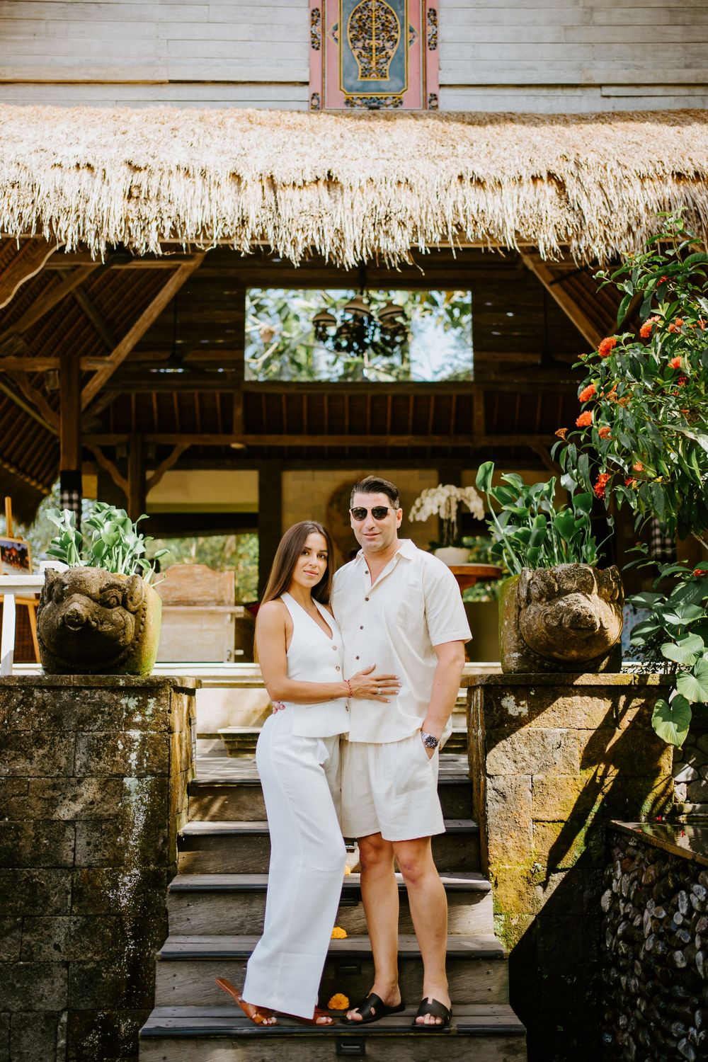 Couple in white outfits sitting together at a traditional Balinese temple structure.