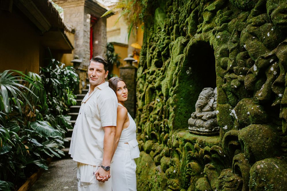 Romantic photoshoot in a tropical garden with stone architecture and lush greenery.