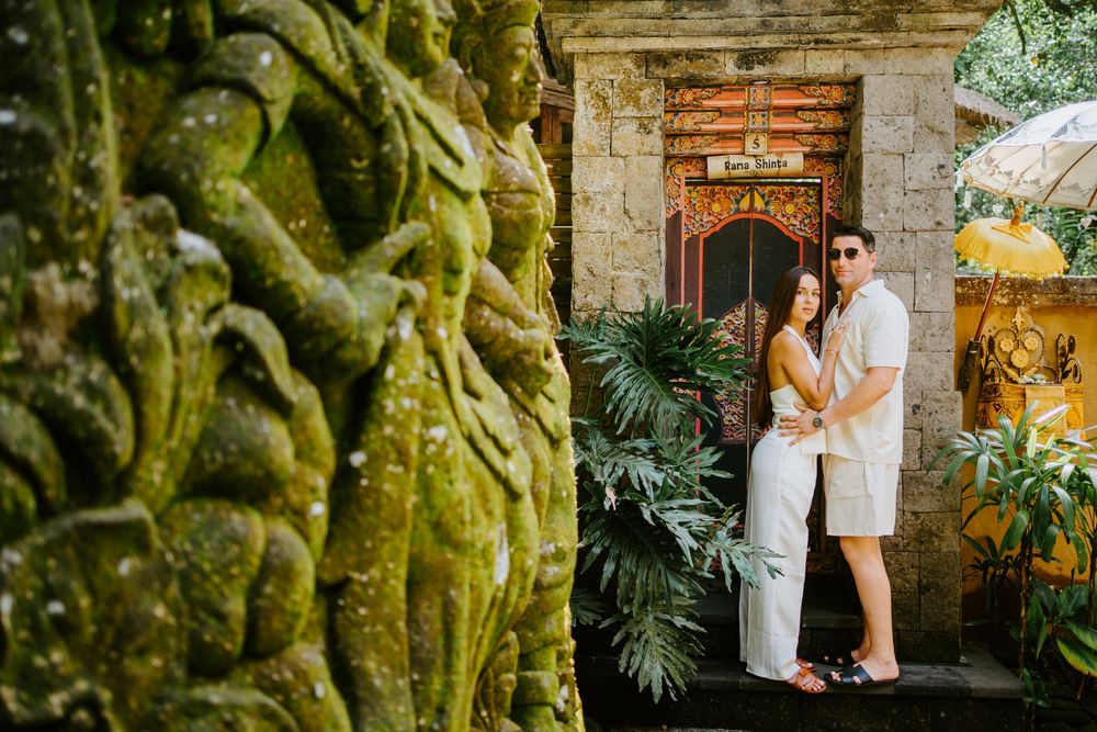 Couple poses along stone pathway surrounded by moss-covered walls and tropical plants.