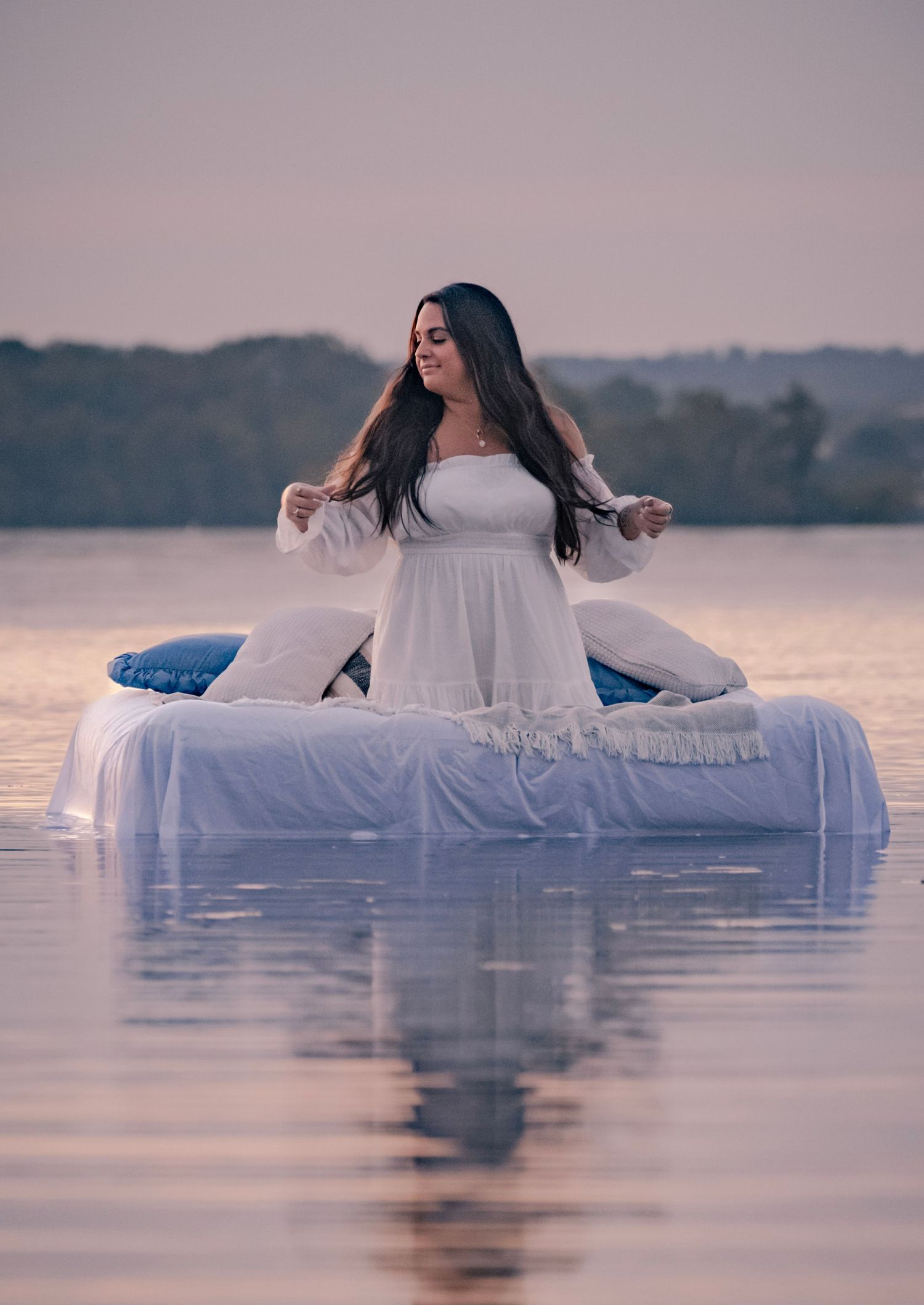 A dreamy scene of a white mattress floating on calm water at sunset creating an ethereal atmosphere.