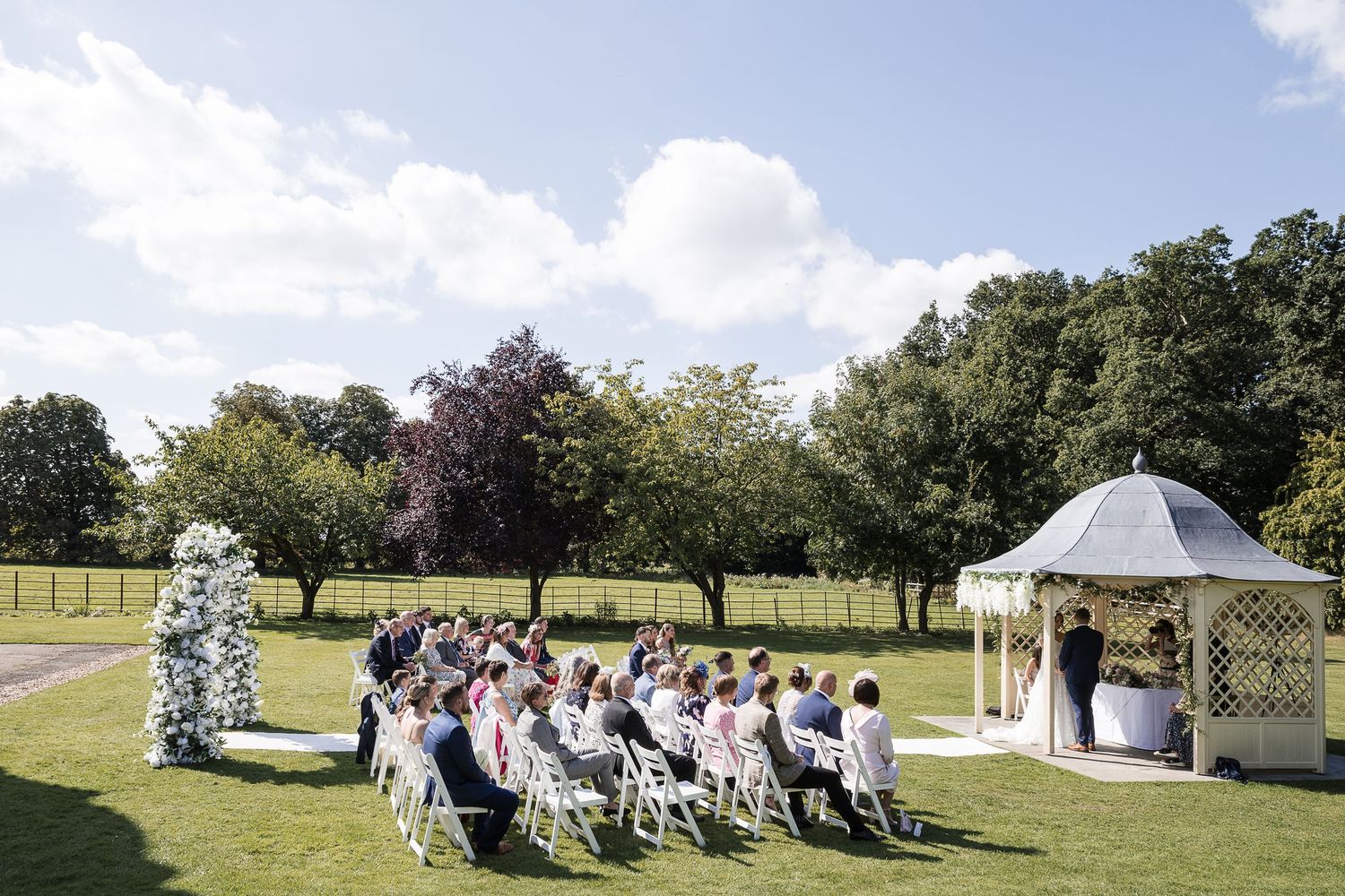 Bride and groom exchanging vows at the Kelham House wedding gazebo with woodland backdrop