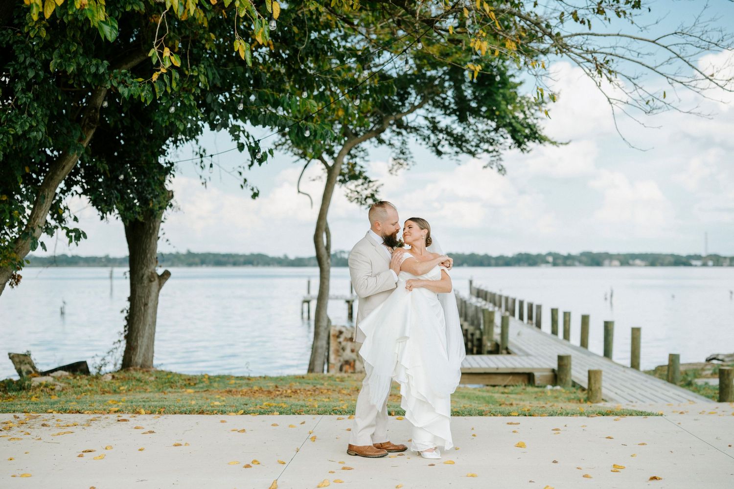 A romantic waterfront scene with trees and a wooden pier stretching along a serene lake.