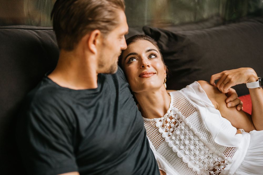 Couple sharing intimate moments on a red and white checkered surface in a romantic indoor setting.