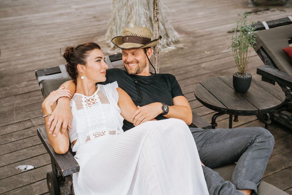 Couple enjoying romantic moments on wooden deck with vintage-style interior decor.