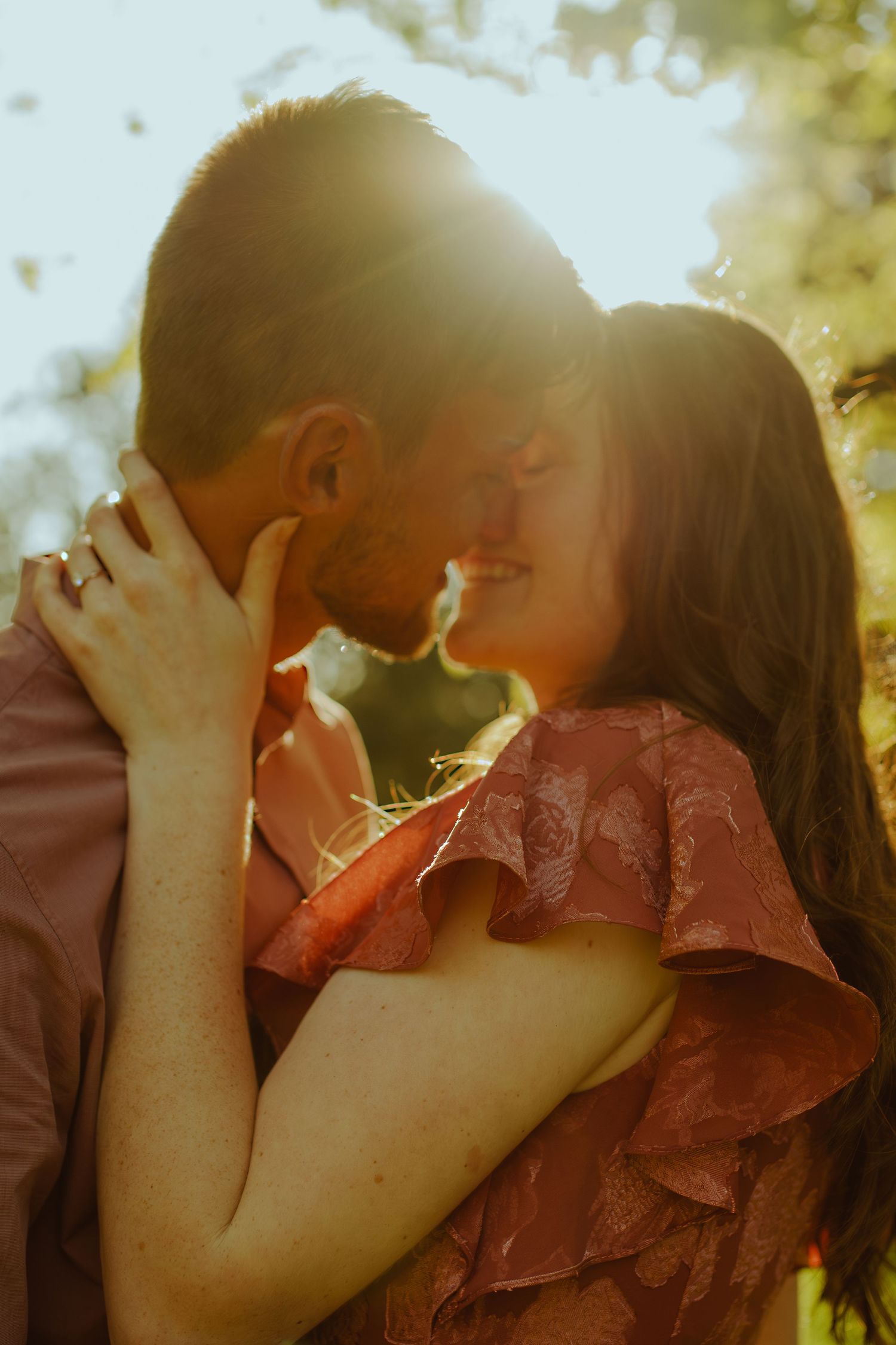 A tender romantic moment captured in dreamy golden hour lighting outdoors.