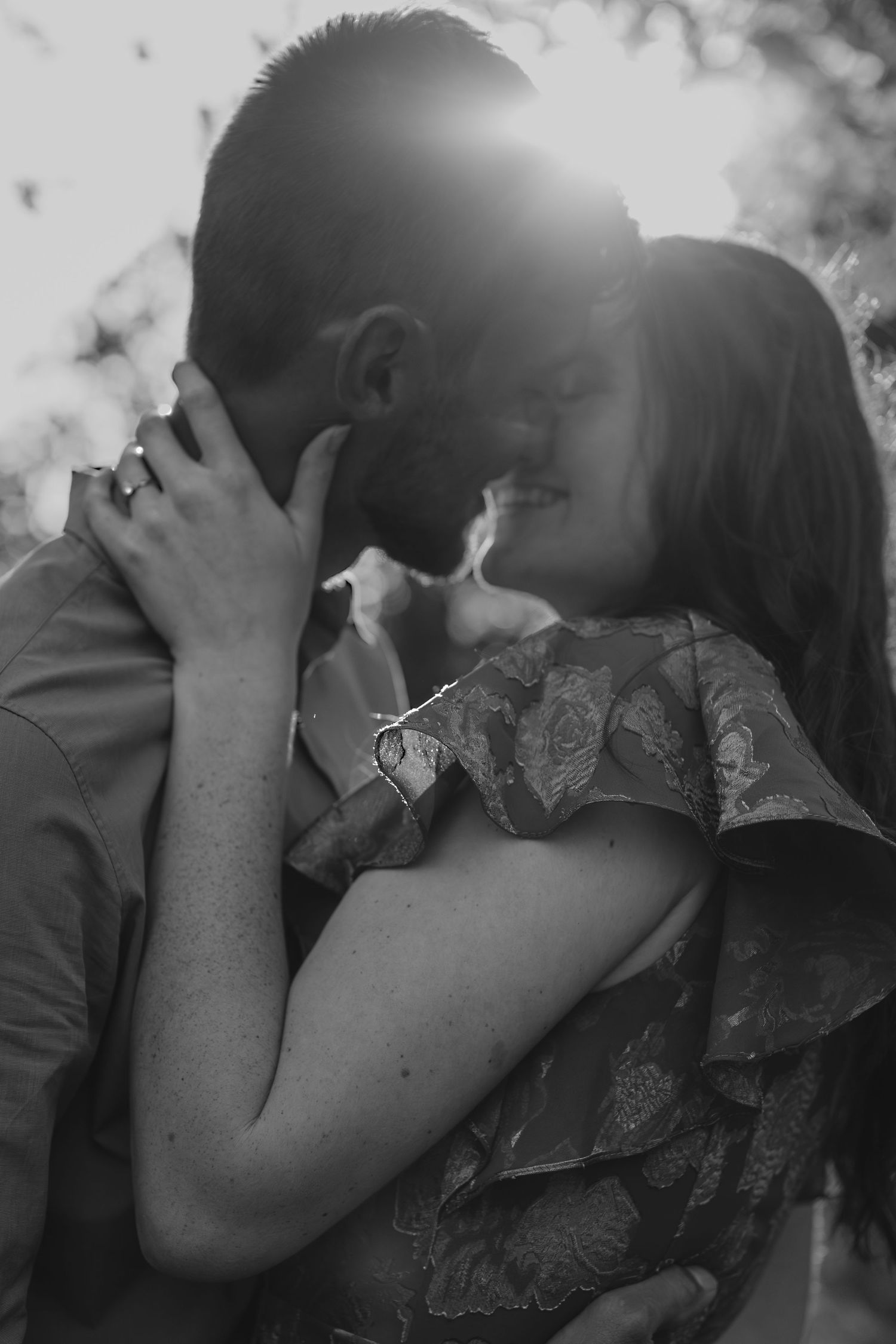 A tender intimate moment captured in black and white photography with soft natural lighting.
