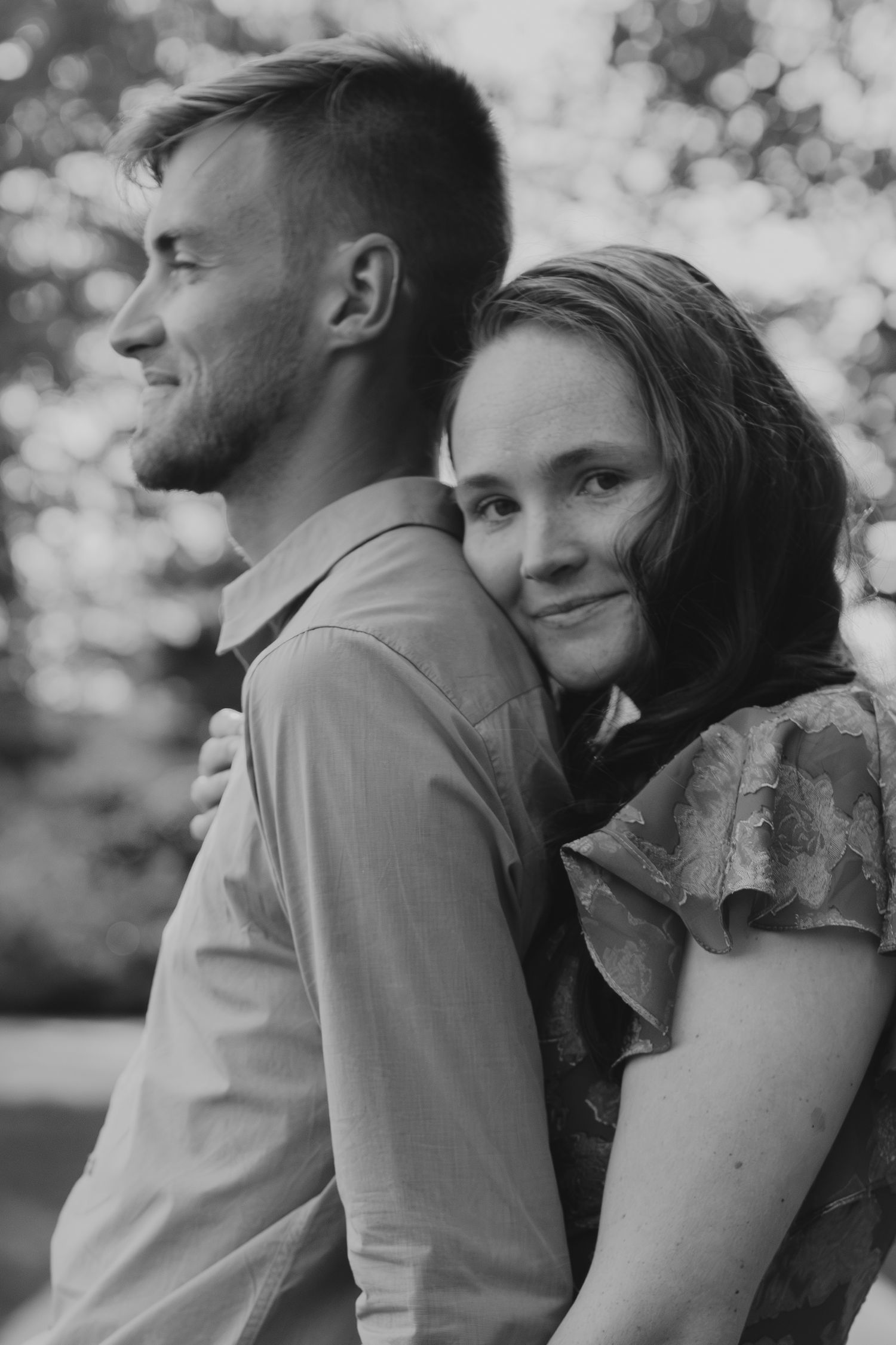 Black and white portrait of a couple sharing an intimate embrace outdoors.