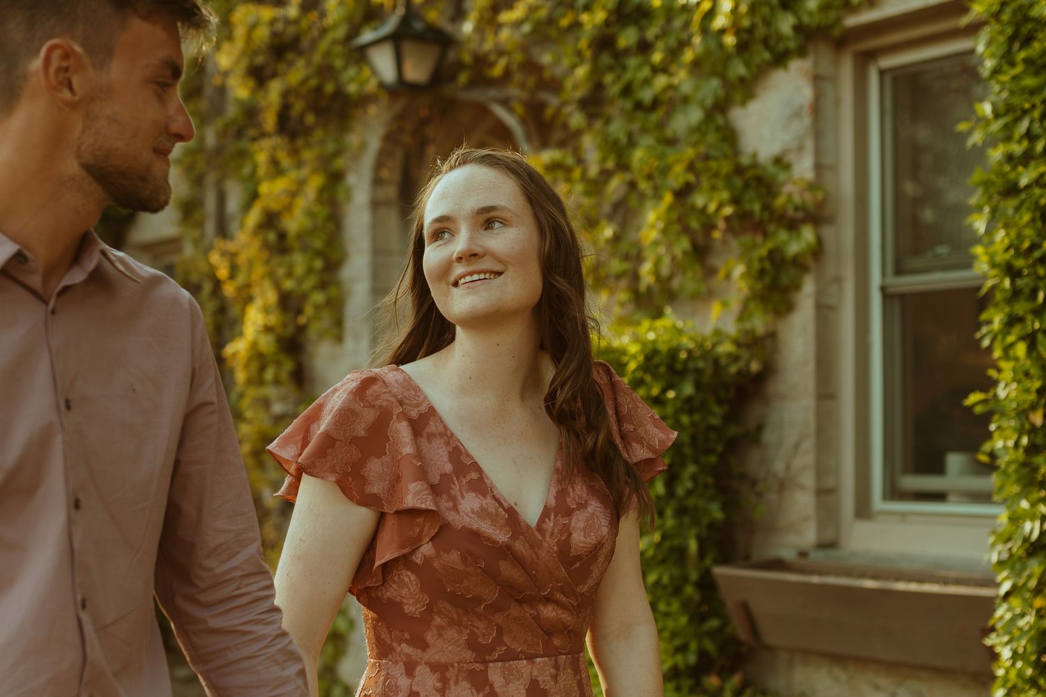 A romantic moment captured outdoors with warm sunlight filtering through trees in the background.