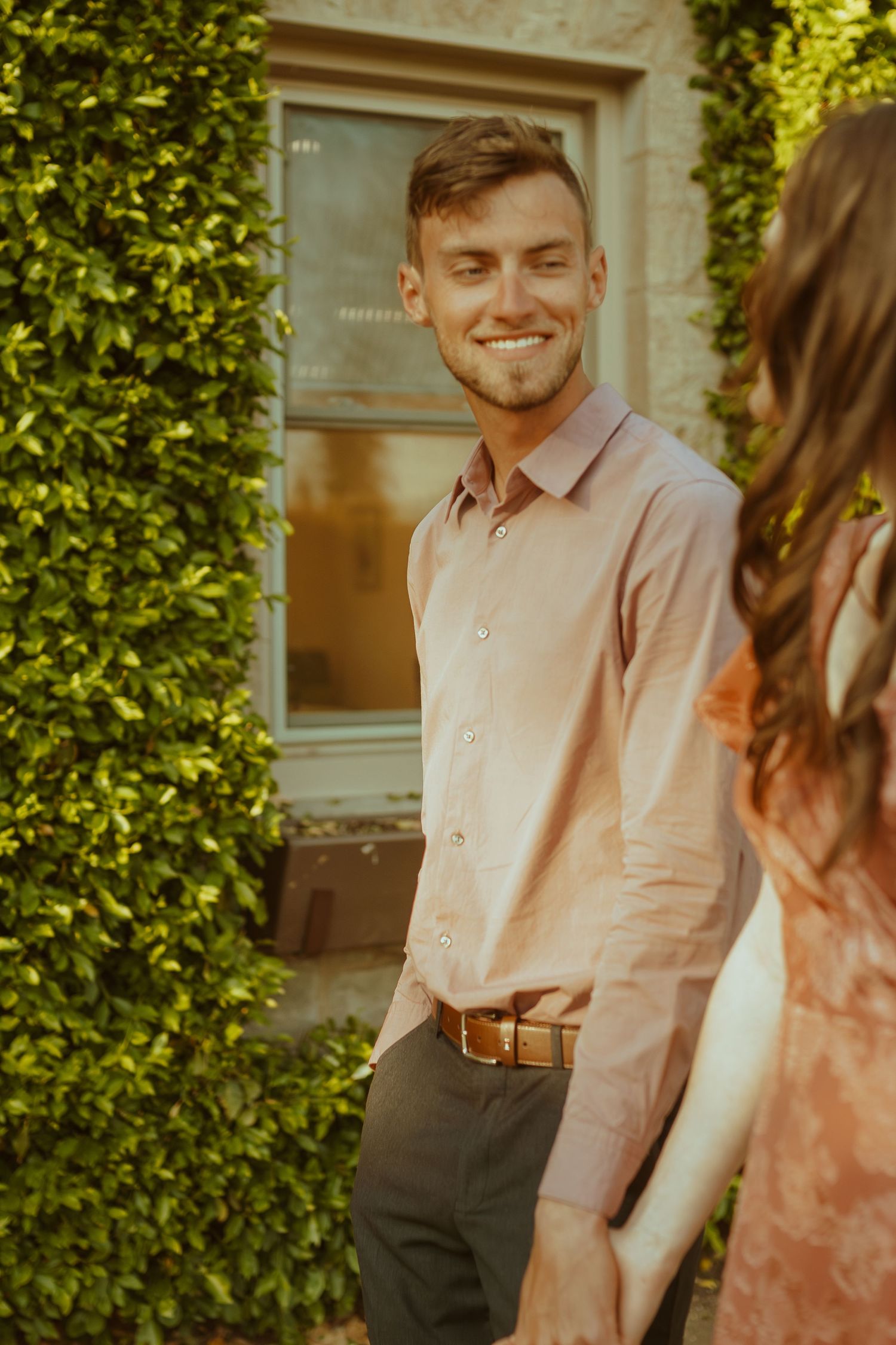 A happy couple shares playful moments in a garden setting during golden hour.
