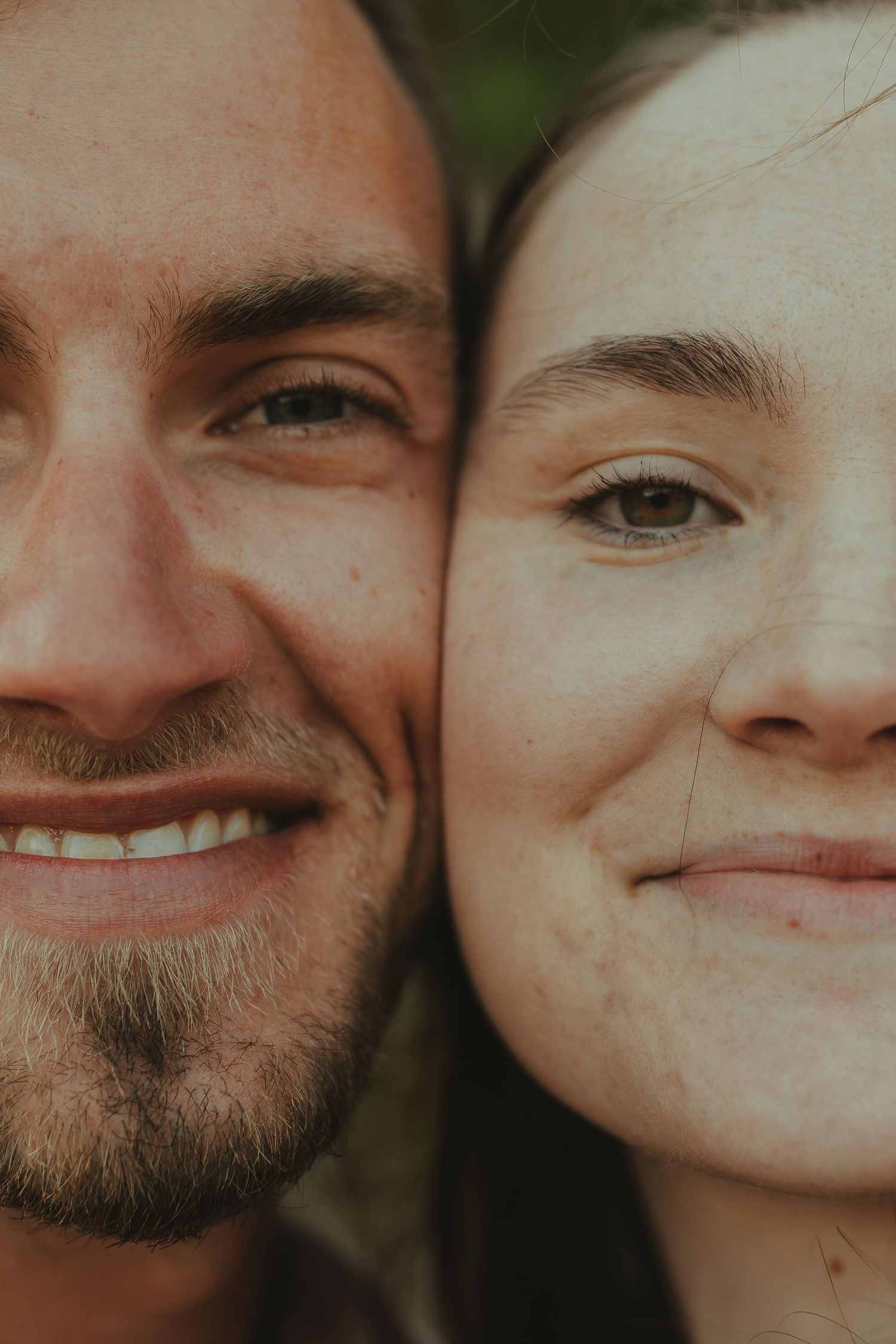 Close-up portrait of a couple sharing joyful smiles together outdoors.
