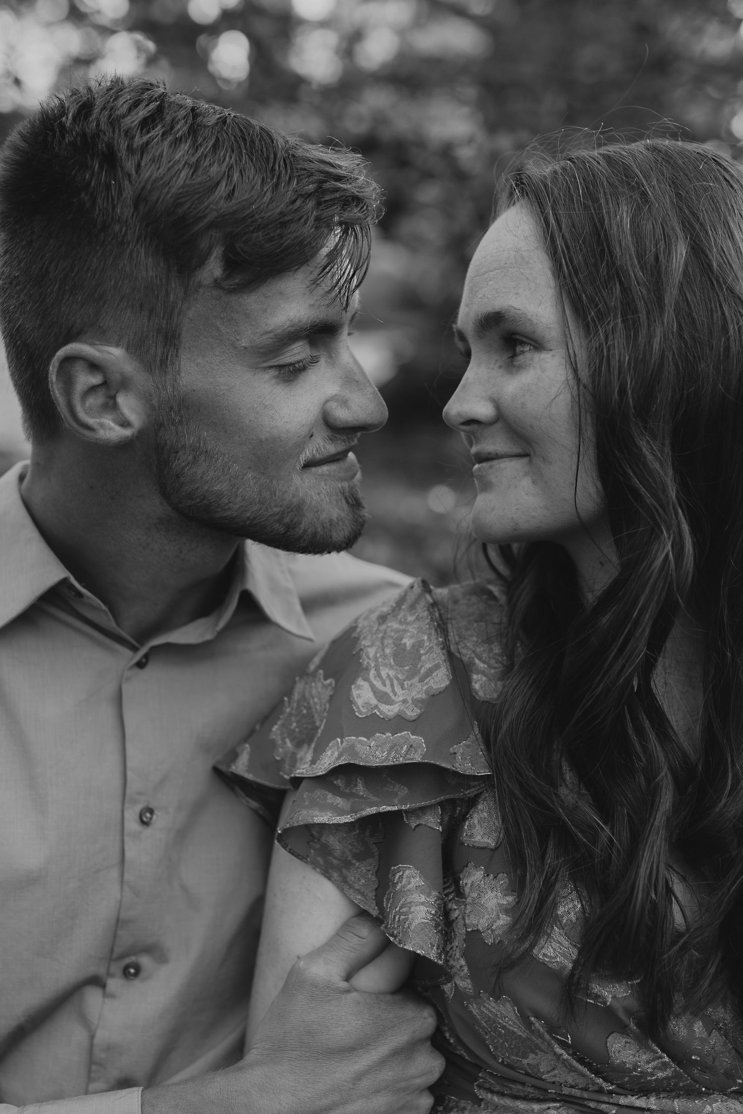 Black and white portrait of couple sharing intimate moments in a dreamy outdoor setting.