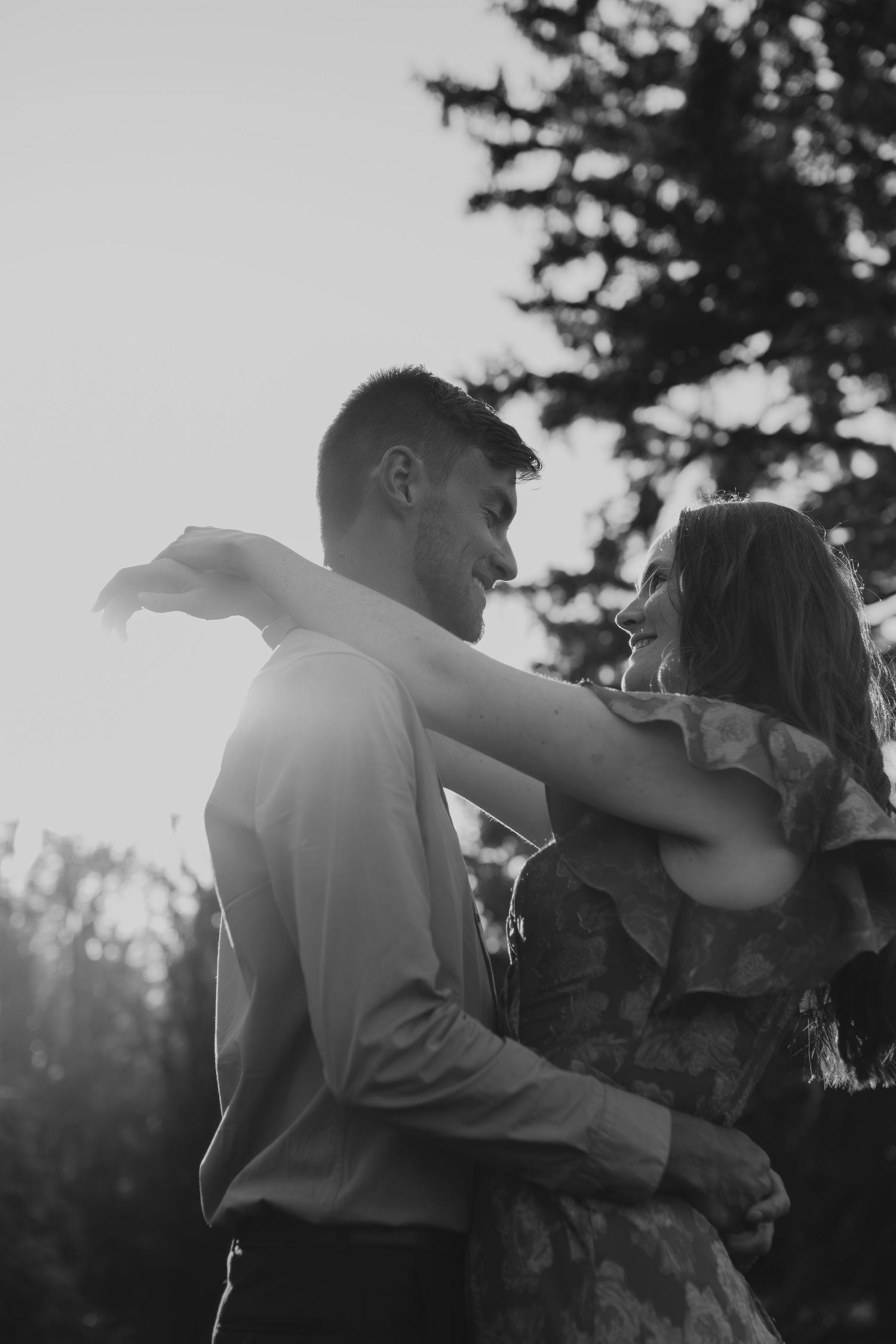 A romantic silhouetted couple embrace and dance together against a moody sunset sky.