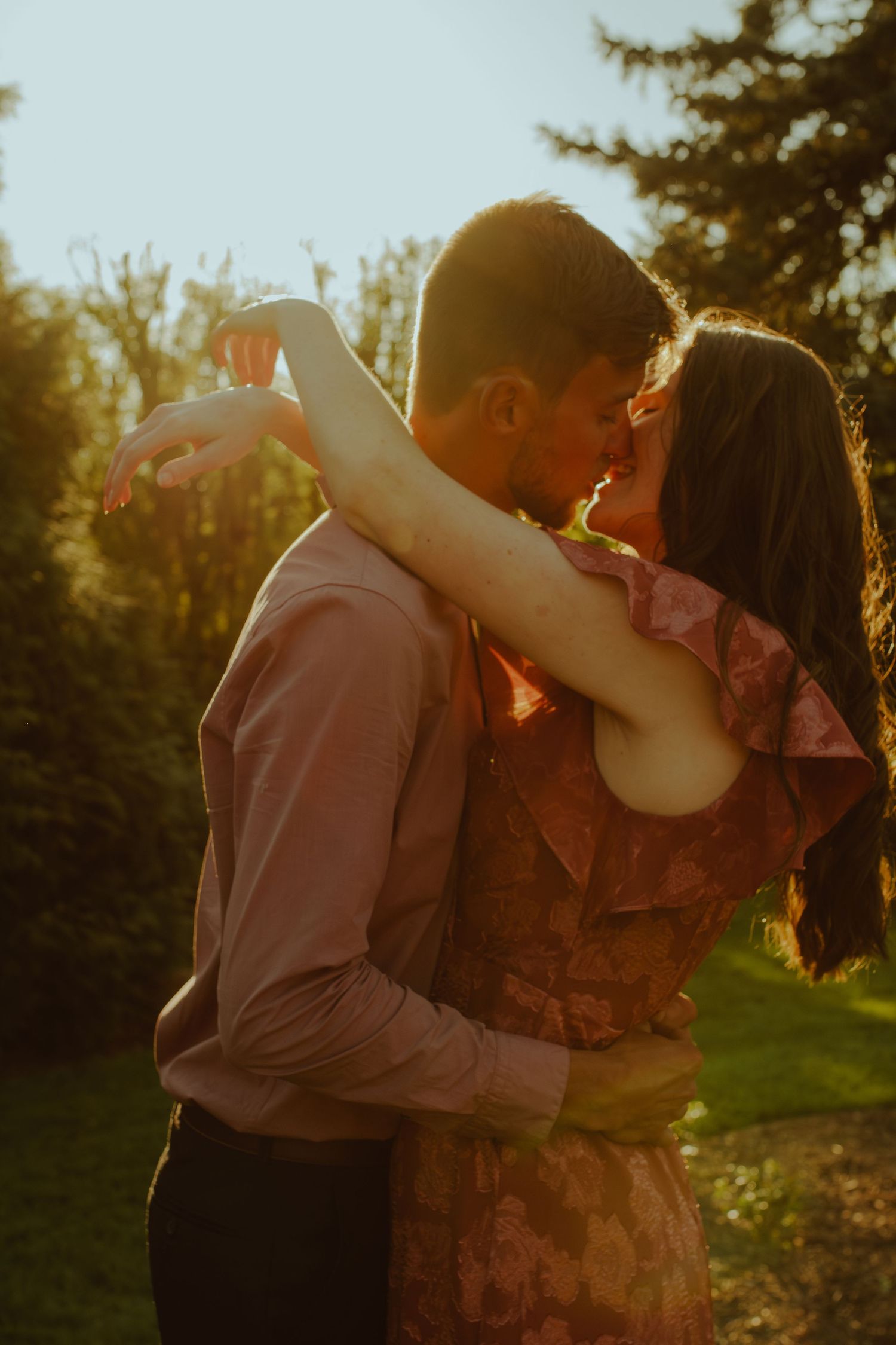 A couple dancing together in a sunny garden during golden hour with warm autumn lighting.